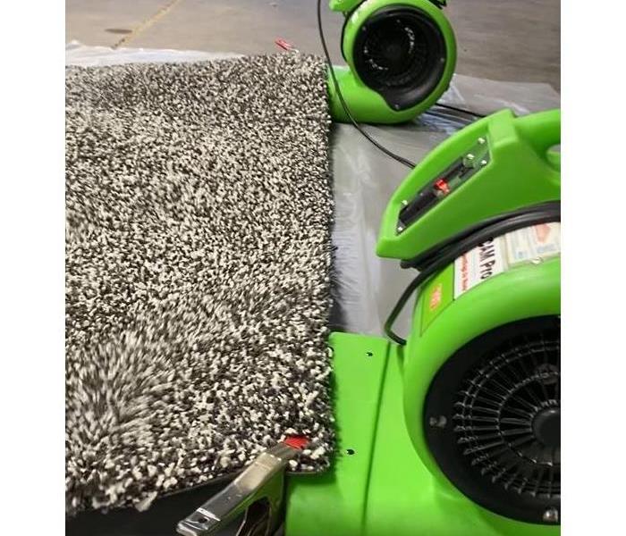 Two air movers with a carpet clipped underneath