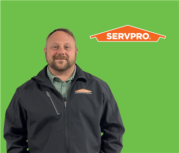 SERVPRO employee with dark hair wearing a black jacket in front of a green background