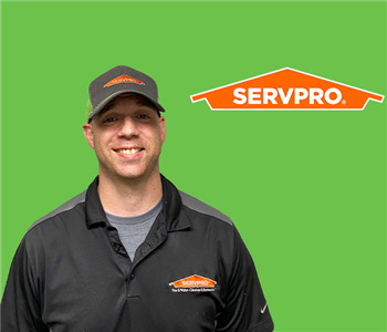 SERVPRO employee with black hat in front of green background