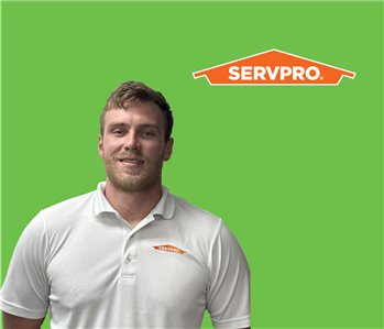 SERVPRO employee with light hair wearing a white shirt in front of a green background